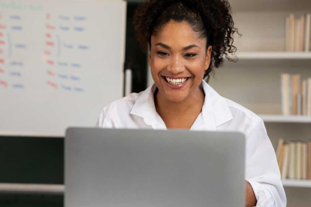 Smiling therapist working on a laptop in a bright office, ready to elevate her therapy practice with a professional website