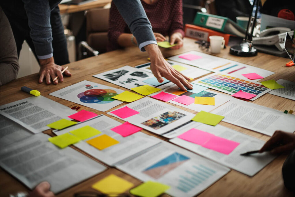 Team planning website content with documents and colorful sticky notes on a table, representing structured digital storytelling for a therapy practice website