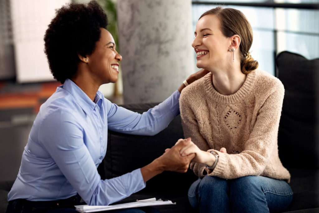 Smiling therapist holding a client’s hands, symbolizing a thriving, purpose-driven mental health practice